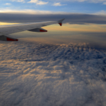 Airplane wing over sunset cloud