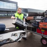 Worker Stacking Luggage On Trailer From Conveyor On Runway