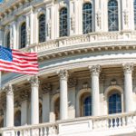 US Congress dome closeup with American flag waving in Washington DC, USA on Capital capitol hill, blue sky, columns, pillars, nobody