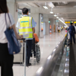 Caretaker pushing elderly people on wheelchair in the airport.