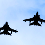 A silhouette of two RAF Tornado jet fighters against a blue sky.