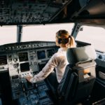 Woman pilot sitting in aircraft cockpit, flying the plane.