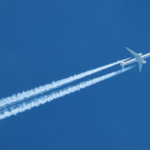Jet airplane flying overhead in clear blue sky diagonally with c
