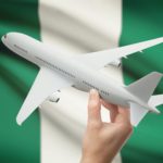 Airplane in hand with flag on background - Nigeria