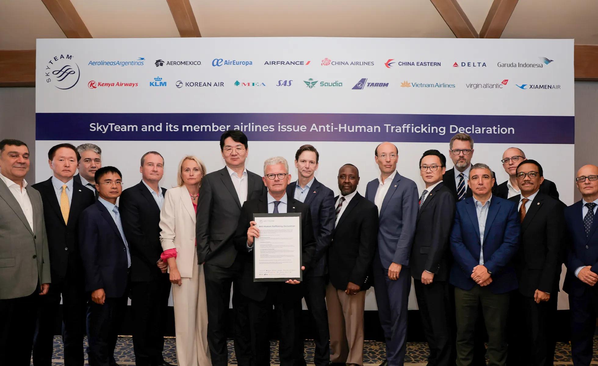A group of airline executives and officials pose together at a formal ceremony where SkyTeam alliance and its member airlines signed an Anti-Human Trafficking Declaration, with one person holding the signed document in the center of the group.