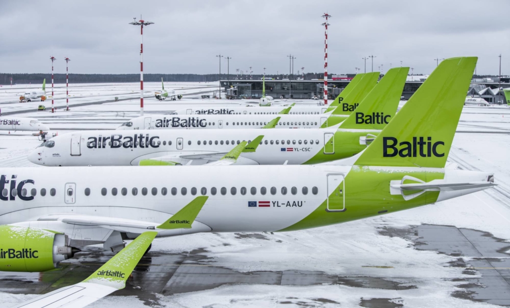 airBaltic A220 aircraft lined up at the gate on the ground at the airport.
