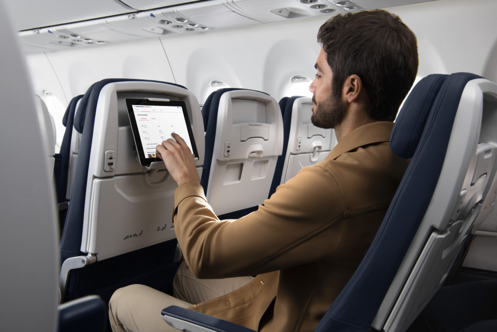 Airbus A220 Cabin in Air France with a person using the in flight entertainment system.