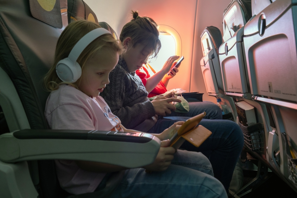 Young passengers with electronic devices using in-flight WiFi