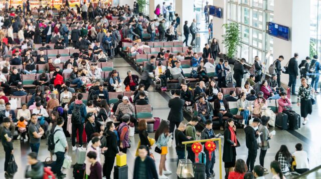 Xiamen, China - March 1, 2019: Larger group of Chinese passengers waiting for boarding call at Xiamen airport.