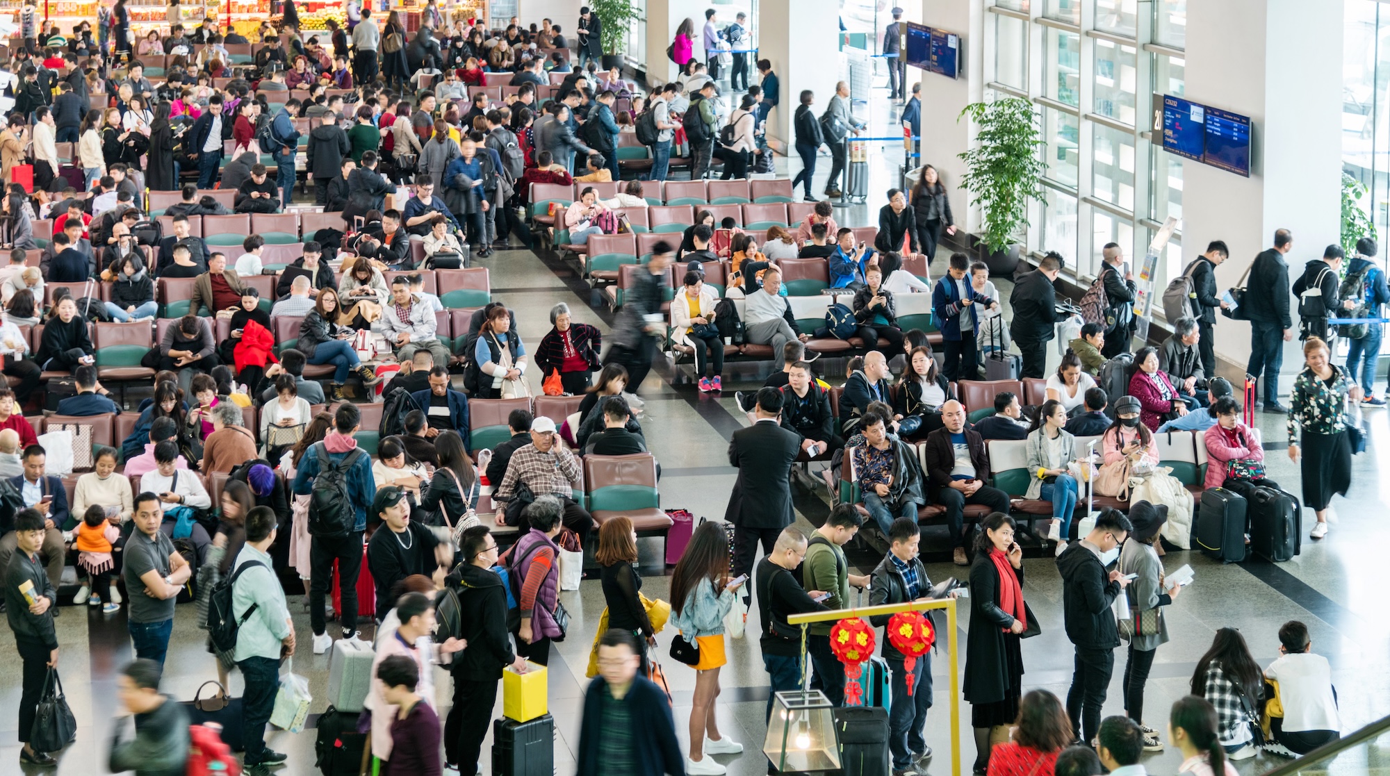 Xiamen, China - March 1, 2019: Larger group of Chinese passengers waiting for boarding call at Xiamen airport.