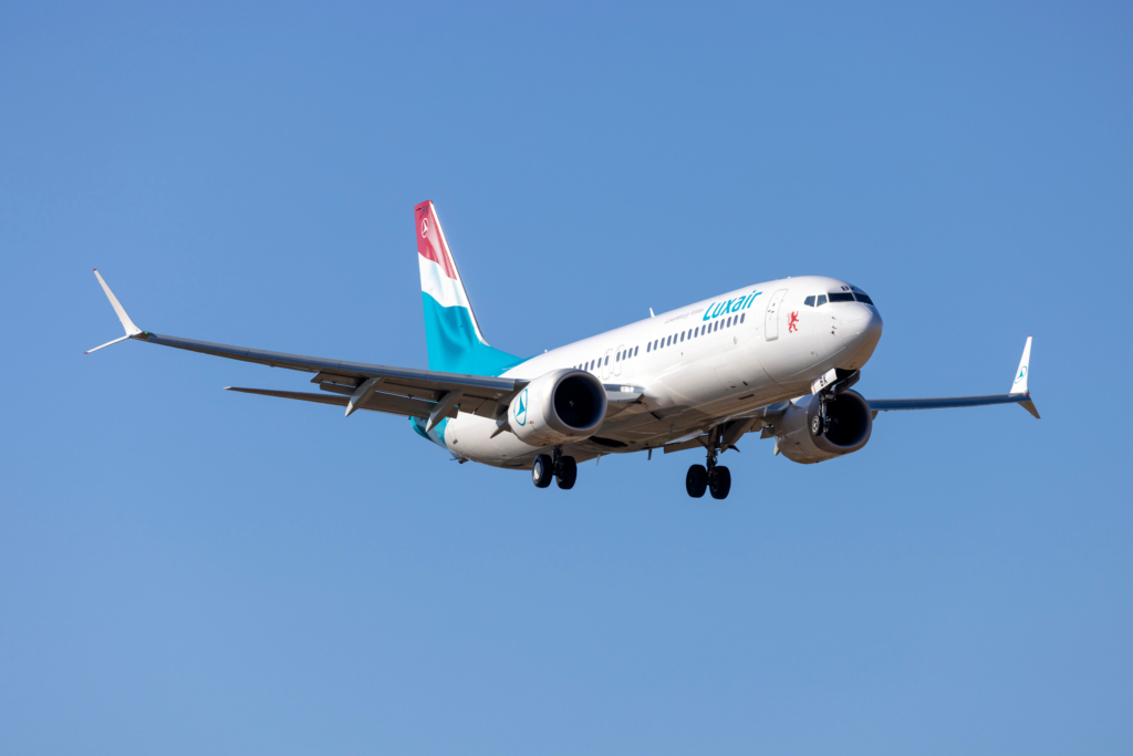 Luxair Boeing 737 MAX aircraft landing in Malta in front of a blue sky.