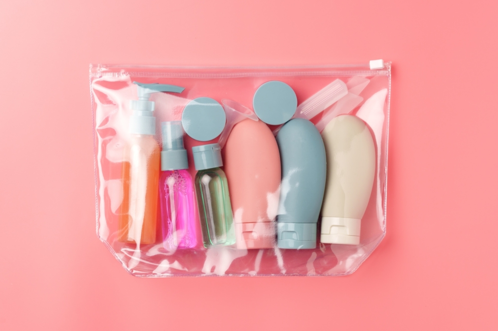 Clear Plastic Bag Containing Travel-Sized Toiletries on Pink Background close up