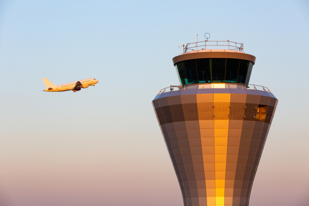 A jet aircraft flying past an air traffic control tower as it takes of at Birmingham Airport in England, UK