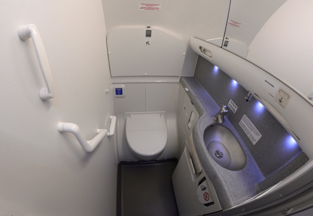 Bathroom of passenger aircraft Boeing 737. Toilet bowl, sink, knob to drain water, seatcovers, handrails