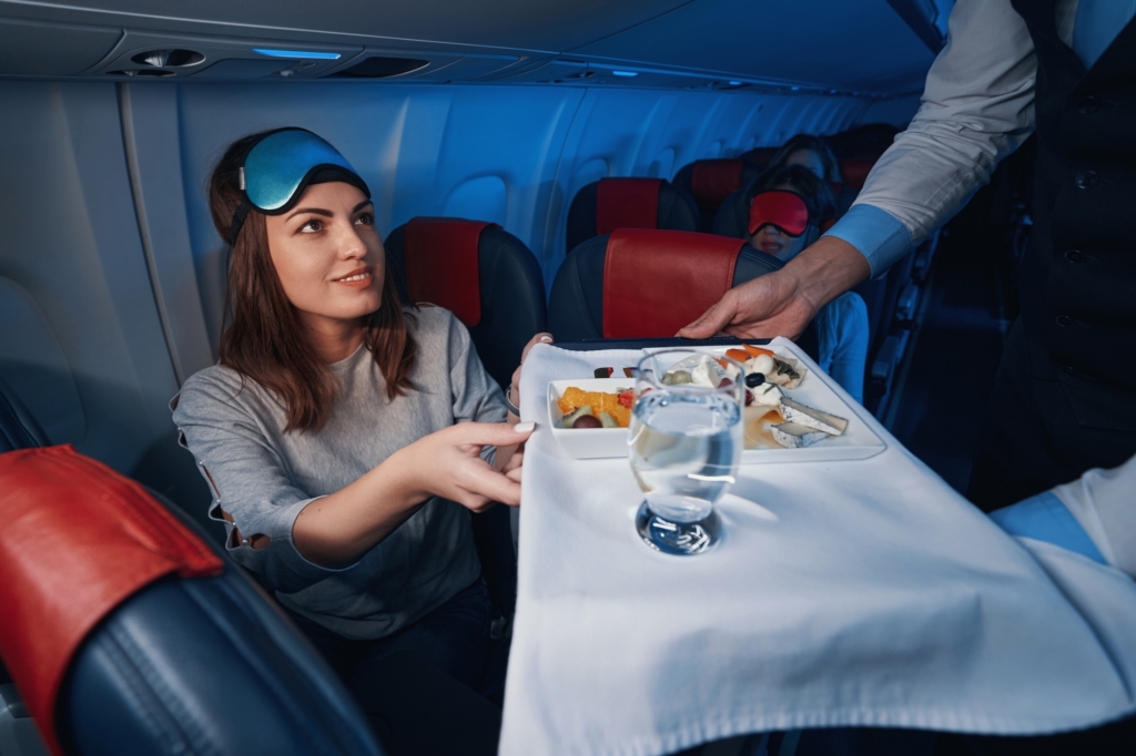 Passenger on aircraft taking meal tray from flight attendant