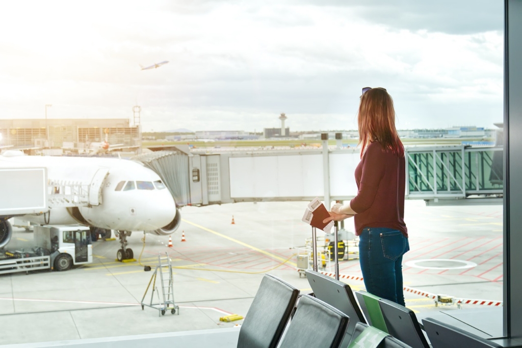 Woman at the airport window and flight departure, Airport Terminal: Happy Traveling Looks Around, Wondering on Vacation.