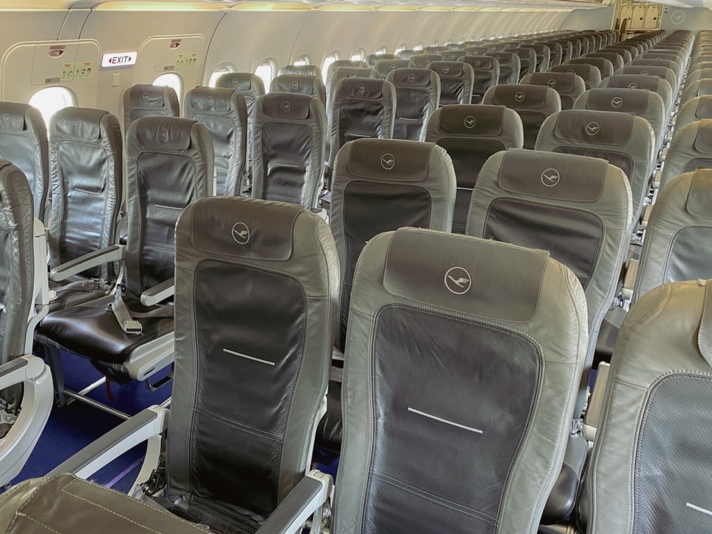 View of European Economy Class cabin with leather seats and luggage compartments onboard Lufthansa Airbus A320 before boarding at Munich Airport taken on 9 May 2023