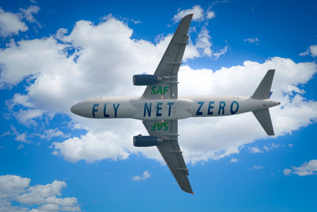 Aircraft soars through the sky with a prominent 'SAF' and 'Fly Net Zero' label on it. Experience the future of carbon-neutral flying and the positive impact of renewable aviation fuel or SAF