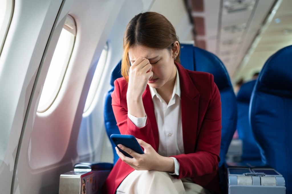 Tired asian woman with headache feeling sick while sitting in the airplane , Passengers near the window.
