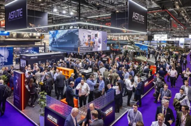 Crowd attending DSEI UK defence and security exhibition in London with military vehicles and industry stands on display