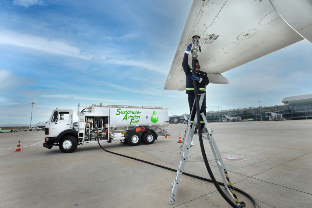 Technician is refueling aircraft with Sustainable Aviation Fuel (SAF) at the airport.