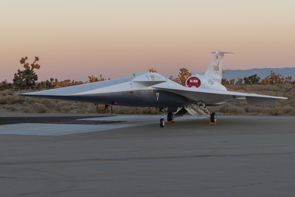 NASA’s X-59 quiet supersonic research aircraft sits on the ramp at Lockheed Martin Skunk Works in Palmdale, California during sunrise, shortly after completion of painting. With its unique design, including a 38-foot-long nose, the X-59 was built to demonstrate the ability to fly supersonic, or faster than the speed of sound, while reducing the typically loud sonic boom produced by aircraft at such speeds to a quieter sonic “thump”. The X-59 is the centerpiece of NASA’s Quesst mission, which seeks to solve one of the major barriers to supersonic flight over land, currently banned in the United States, by making sonic booms quieter.