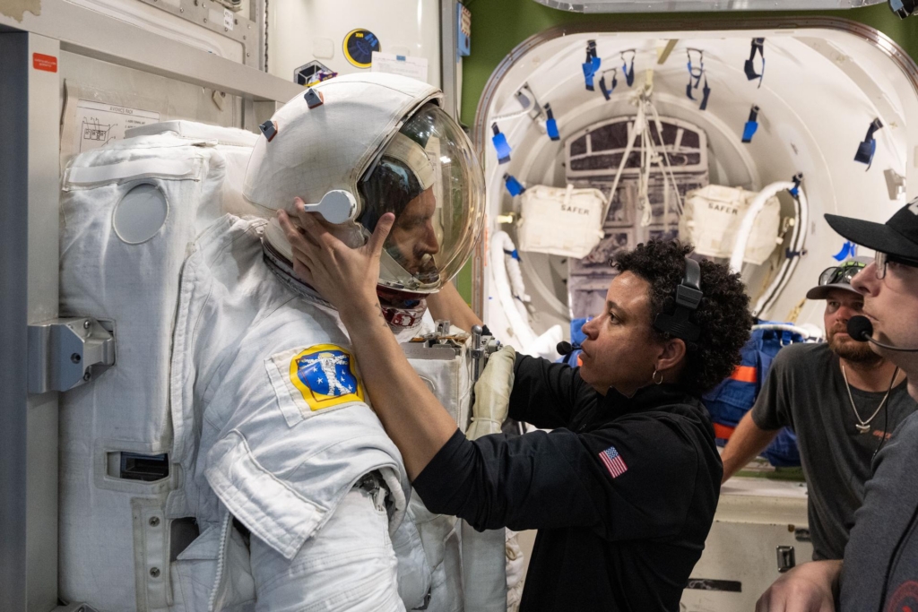 NASA astronaut Jessica Watkins (center) assists Canadian Space Agency astronaut Josh Kutryk as he practices suiting up in a spacesuit in an International Space Station airlock simulator at the Johnson Space Center in Houston, Texas.